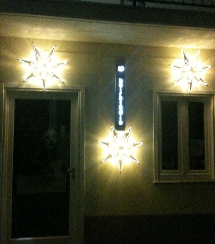L'ingresso di G.P. Hair Studio di sera, con l'insegna verticale nera illuminata e le stelle di Natale sulla facciata